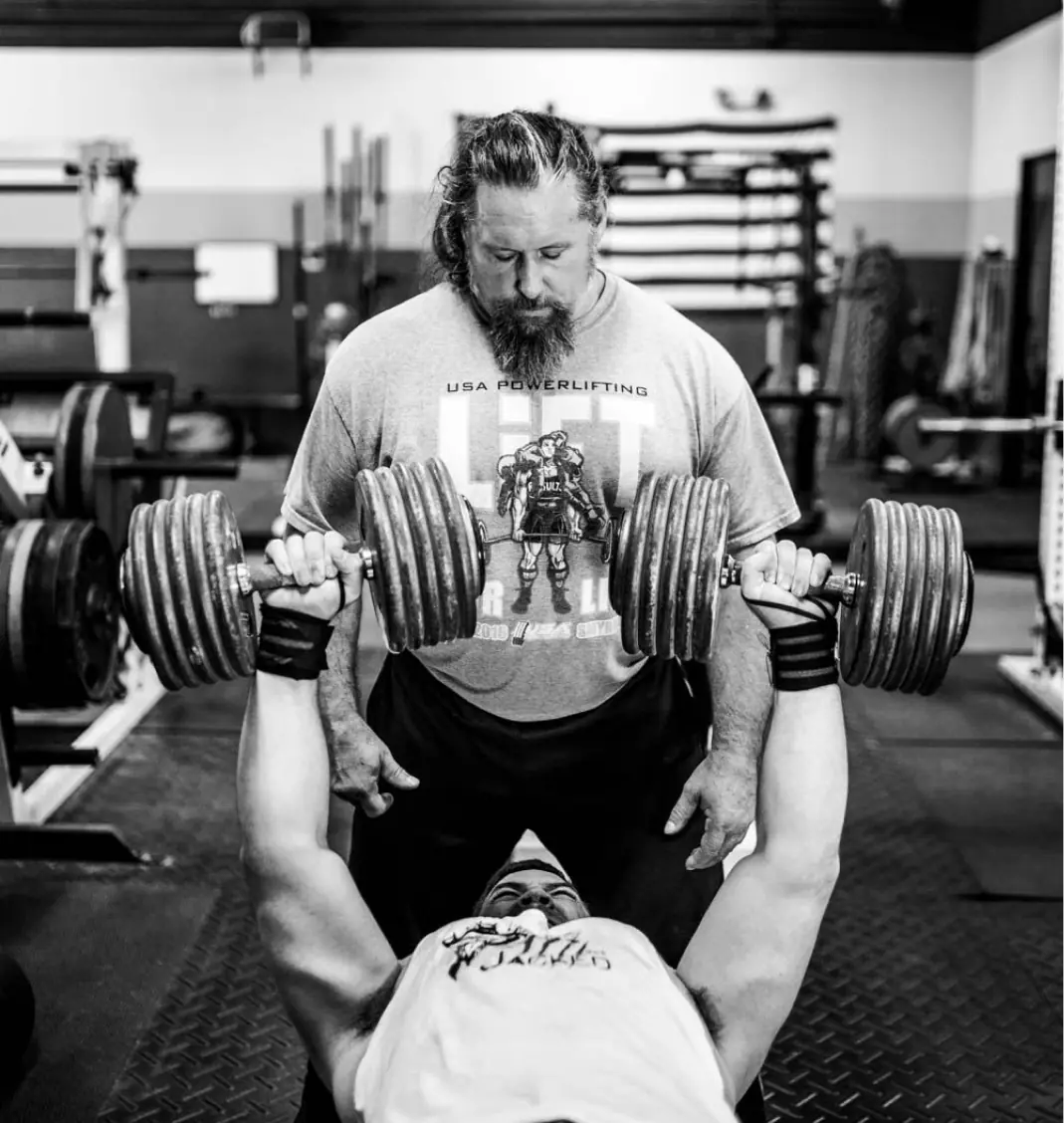 Coach Callahan spotting a lifter through a heavy dumbbell press
