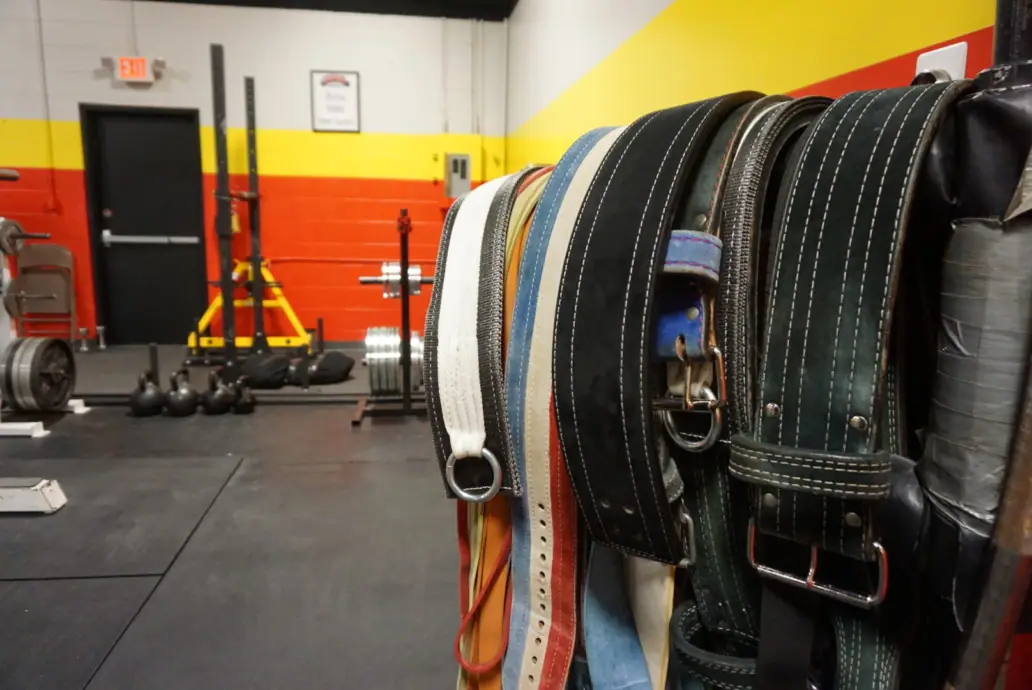 Lifting belts hanging on the gym rack